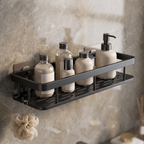 Black adhesive wall-mounted bathroom shelf holding toiletry bottles with a loofah hanging from the side hooks