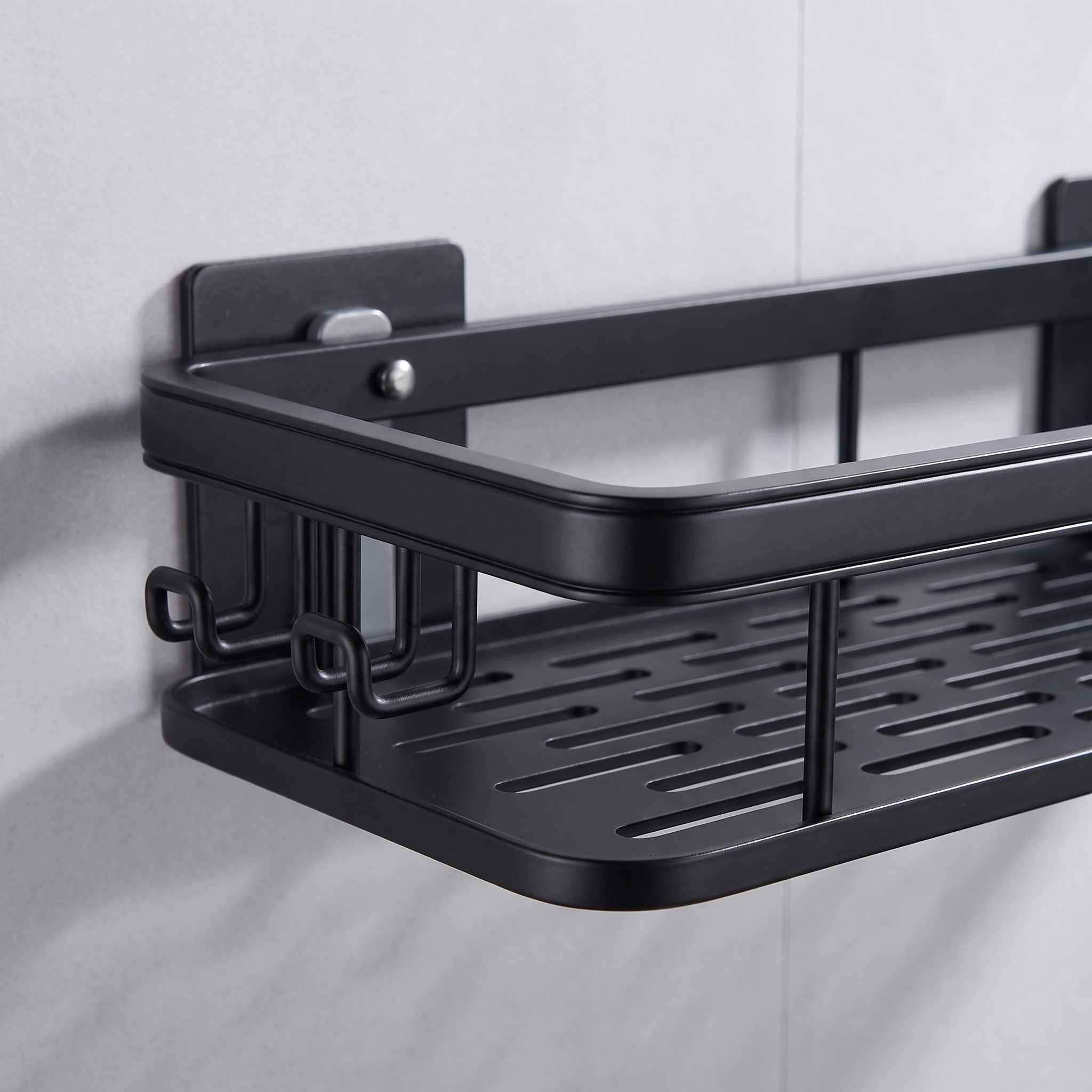 Close-up of the adhesive mounting plate and the three side hooks on the left end of the black bathroom shelf