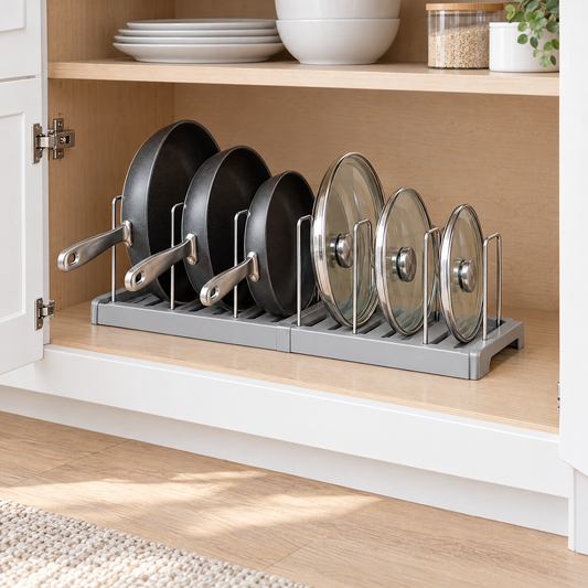 Gray expandable pot and pan organizer rack holding frying pans and glass lids upright inside a kitchen cabinet