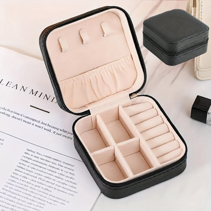 Black travel jewelry case open and empty, showing the pink lining, lid hooks and compartments